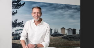Magnus Welander CEO Thulev bílé košili a s pozadím plakátu malých chatek a nosiče kol na autě